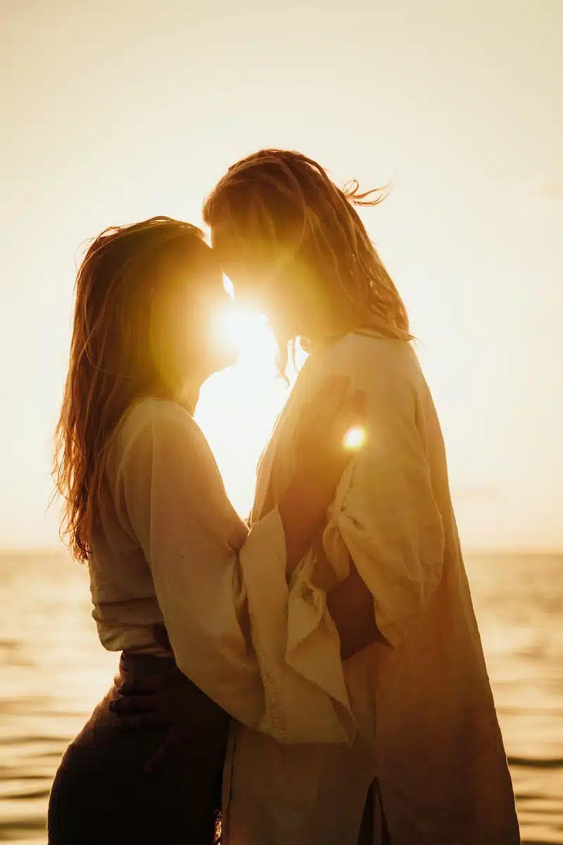 a couple kissing in front of the sun